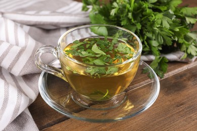 Aromatic herbal tea with parsley on wooden table, closeup