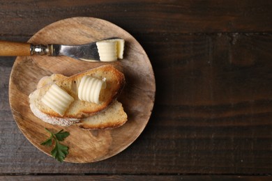 Photo of Tasty butter curls, knife and slices of bread on wooden table, top view. Space for text