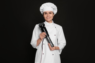 Chef holding sous vide cooker on black background