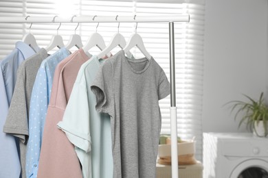 Photo of Different apparel hanging on clothes rack in bathroom, space for text