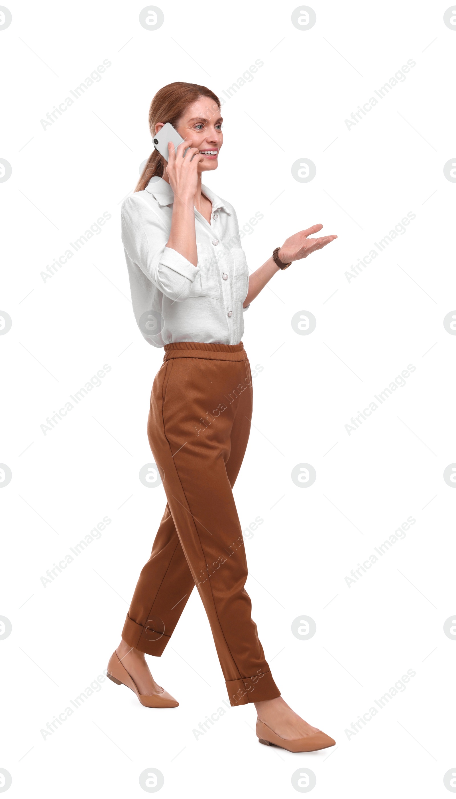 Photo of Beautiful happy businesswoman talking on smartphone while walking against white background