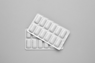 Blisters with chewing gums on grey background, flat lay