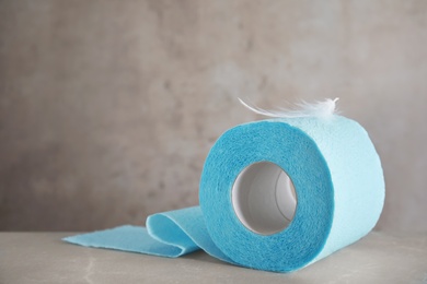 Toilet paper roll with feather on grey background