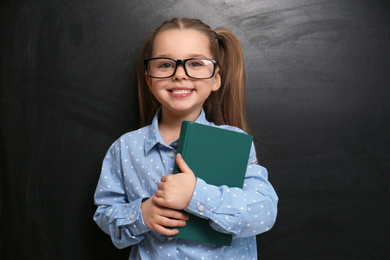 Cute little child wearing glasses near chalkboard. First time at school