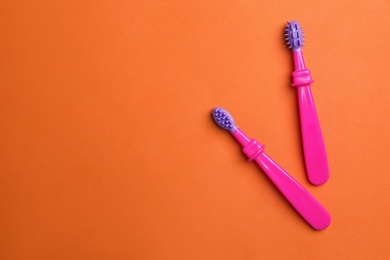 Manual toothbrushes for children on color background, top view with space for text