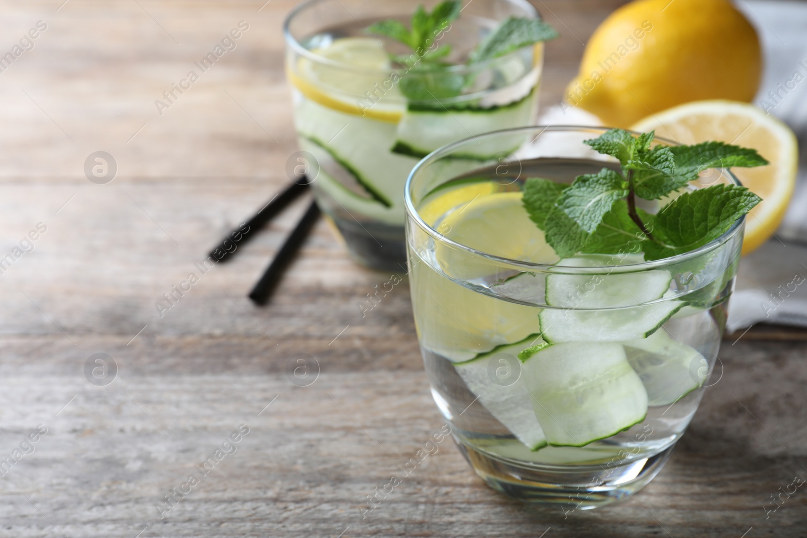 Photo of Refreshing water with cucumber, lemon and mint on wooden table, closeup. Space for text