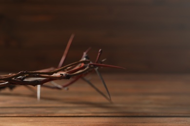 Crown of thorns on wooden table, closeup with space for text. Easter attribute