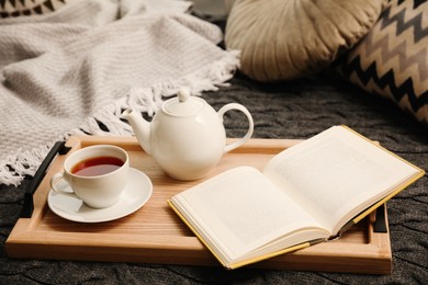Photo of Comfortable place for reading with open book and hot tea