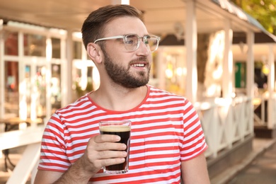 Handsome man with cold kvass outdoors. Traditional Russian summer drink