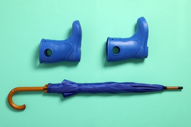 Photo of Flat lay composition with umbrella and rubber boots on color background