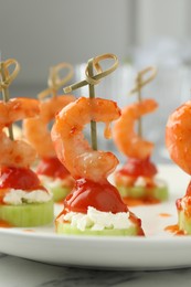 Tasty canapes with shrimps, vegetables and cream cheese on white table, closeup