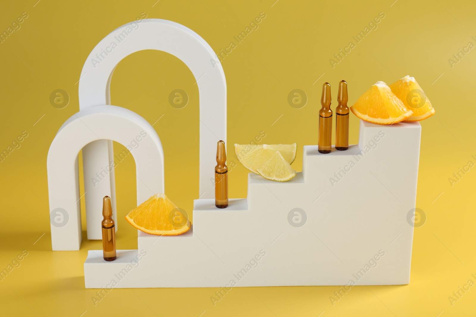 Photo of Stylish presentation of skincare ampoules with vitamin C and citrus slices on yellow background