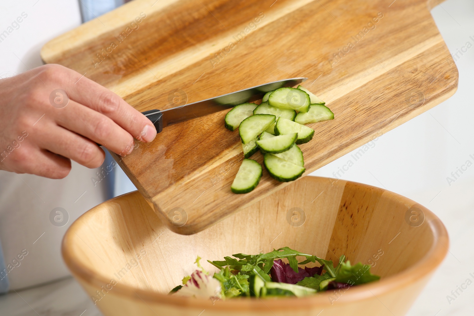 Photo of Man putting cut cucumber into bowl, closeup. Online cooking course