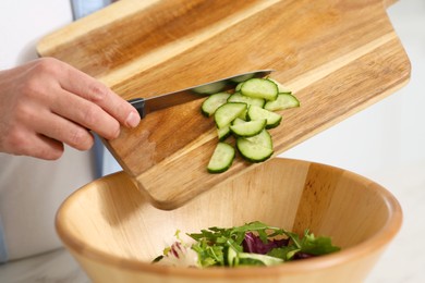 Photo of Man putting cut cucumber into bowl, closeup. Online cooking course