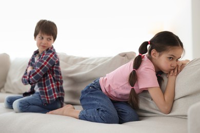 Upset brother and sister on sofa at home