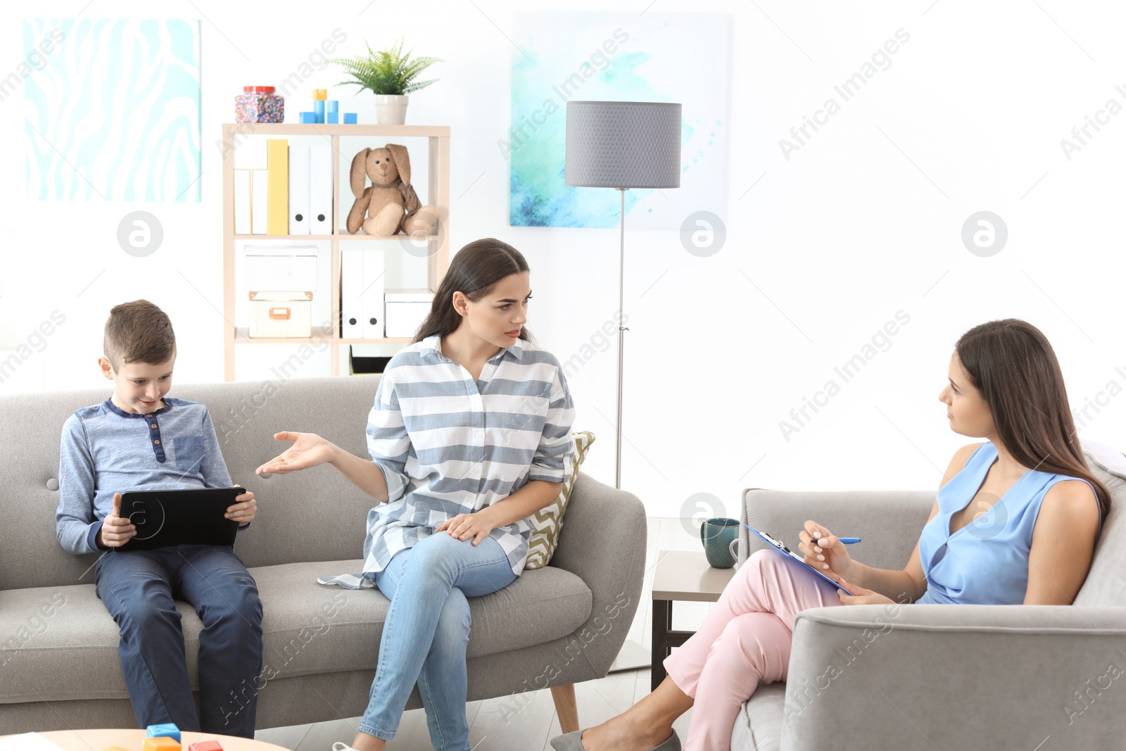 Photo of Young woman and her son visiting child psychologist in office. Computer addiction