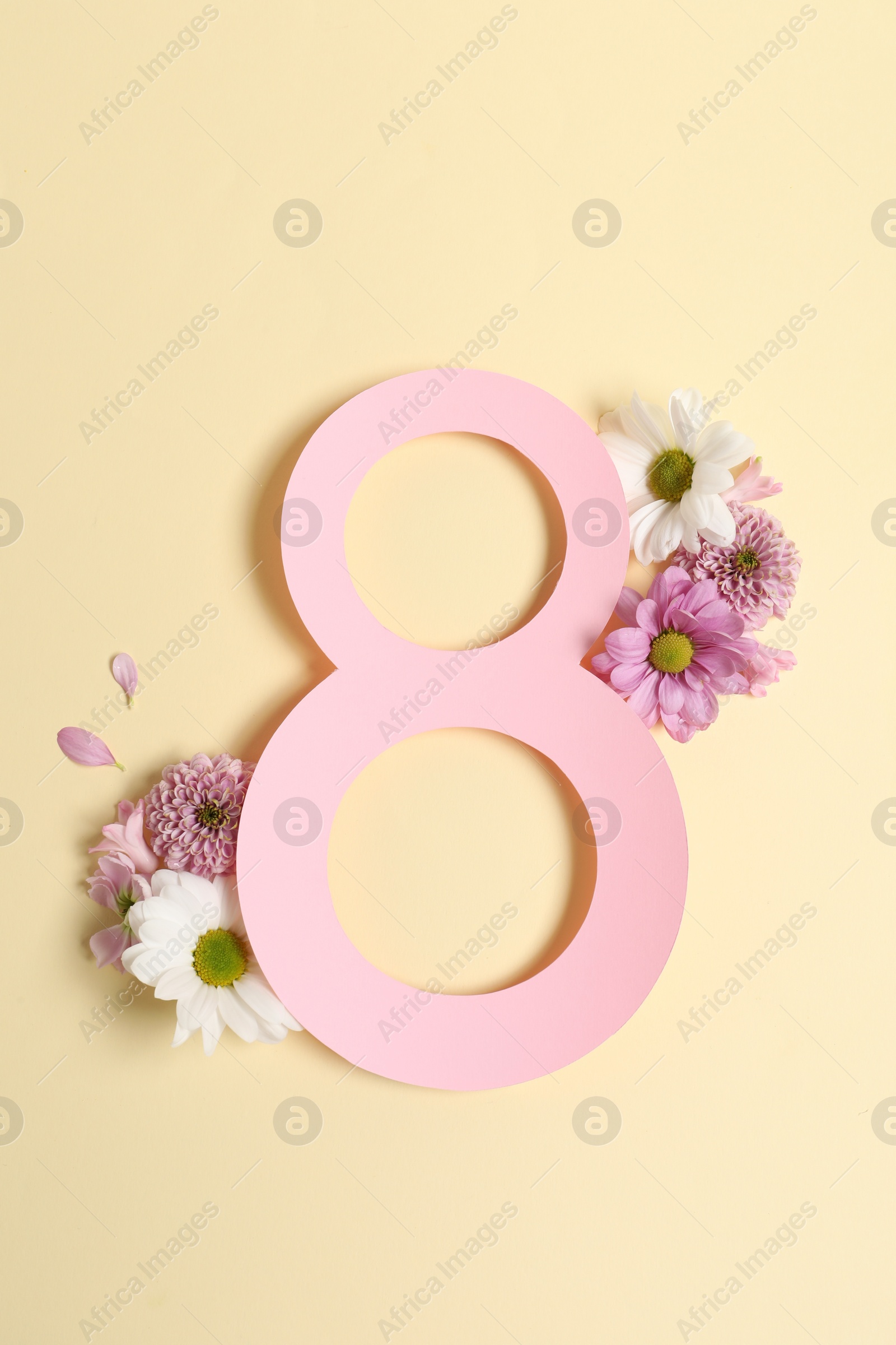 Photo of 8 March greeting card design with beautiful flowers on light yellow background, top view