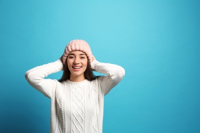 Young woman wearing warm clothes on color background, space for text. Winter season