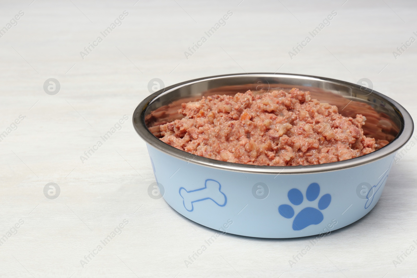 Photo of Wet pet food in feeding bowl on white table