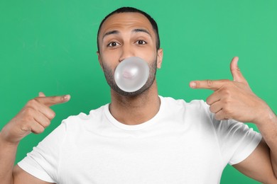 Photo of Portrait of man blowing bubble gum on green background