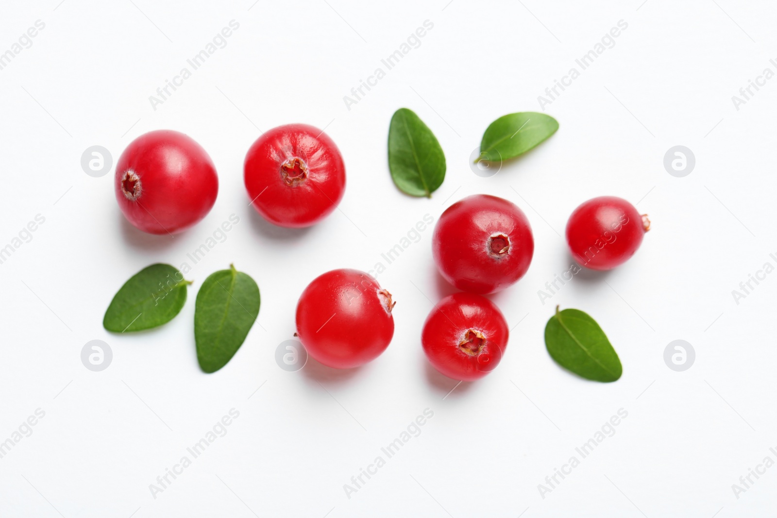 Photo of Fresh ripe cranberries and green leaves on white background, flat lay