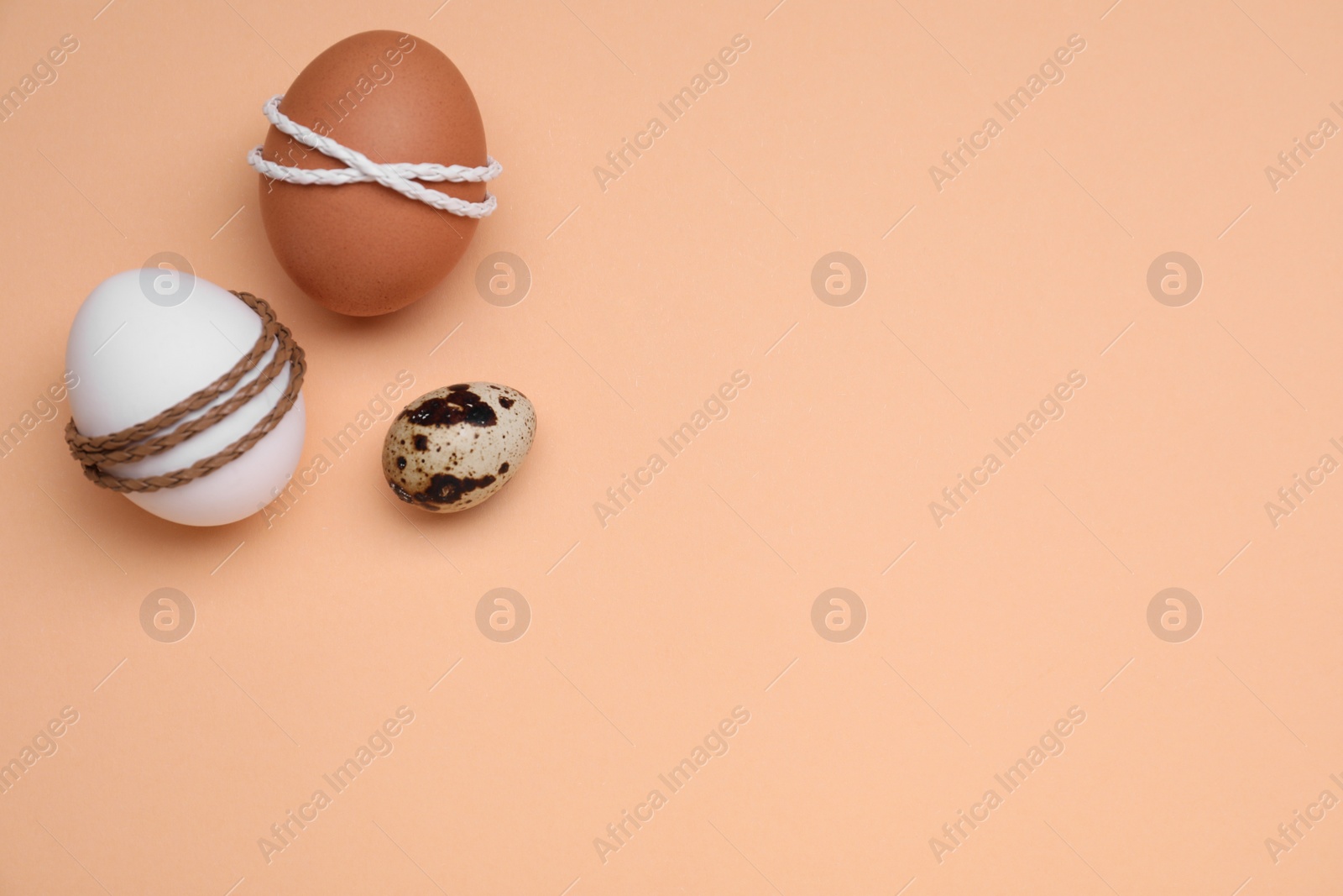 Photo of Beautifully decorated Easter eggs on pale orange background, flat lay. Space for text