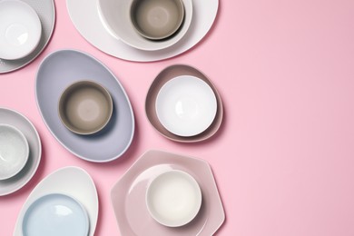Photo of Different plates and bowls on pink background, flat lay. Space for text