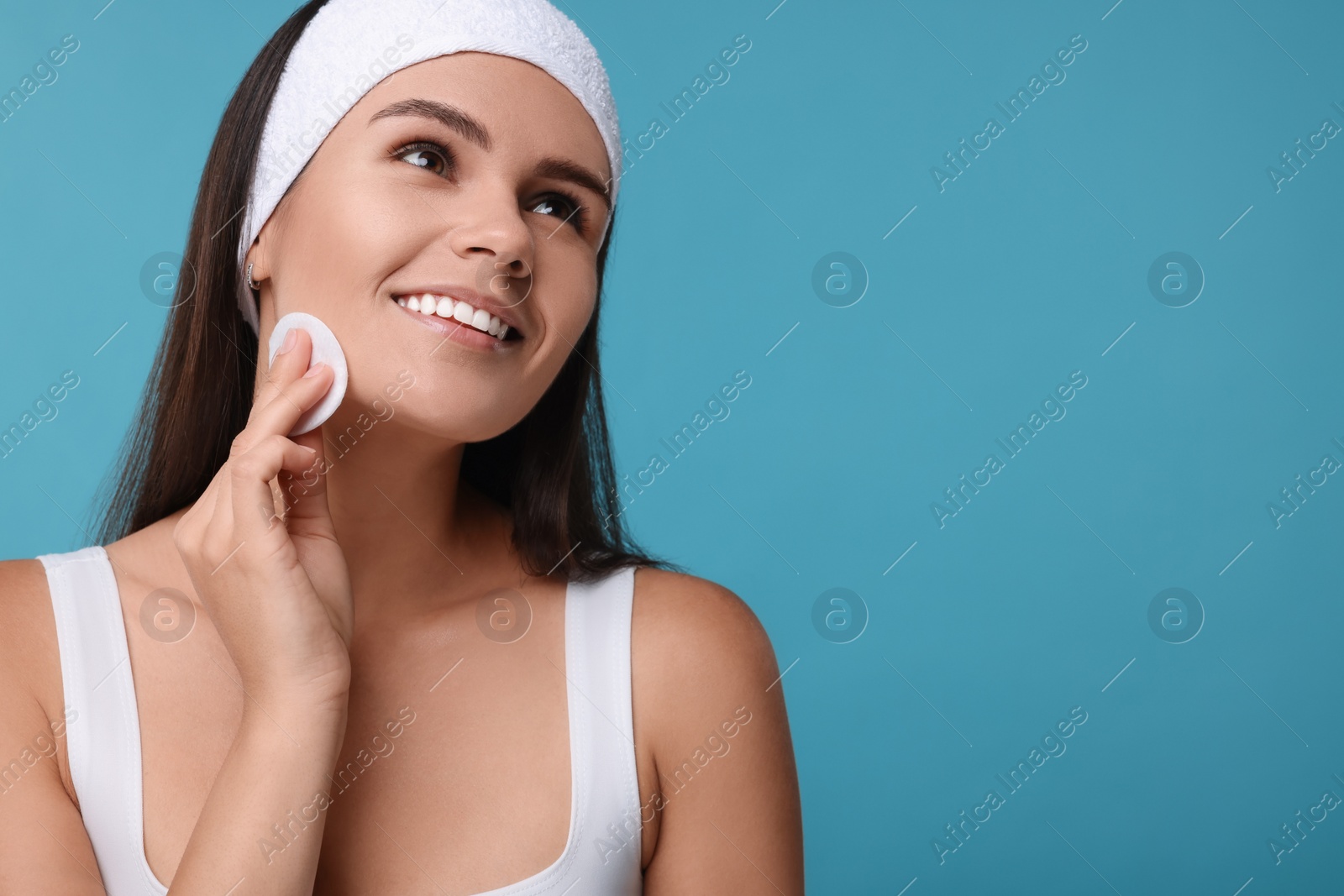 Photo of Young woman with cotton pad on light blue background. Space for text