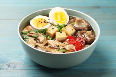 Photo of Bowl of delicious ramen on light blue wooden table. Noodle soup