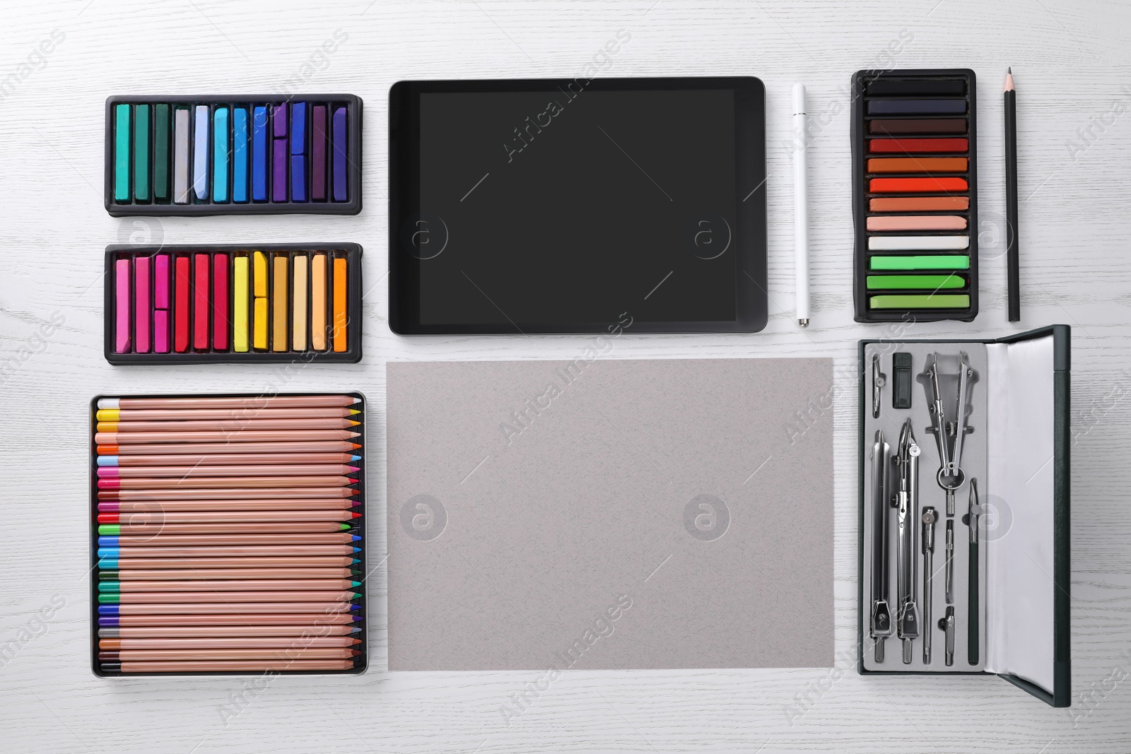 Photo of Layout with blank paper, soft pastels and other drawing supplies on white wooden table at artist's workplace, top view. Space for design