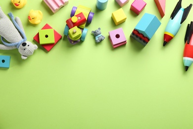 Photo of Different toys on green background, flat lay. Space for text