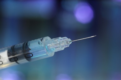 Syringe with medicine against blurred background, closeup