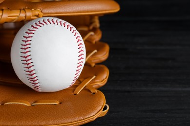 Photo of Catcher's mitt and baseball ball on black background, closeup with space for text. Sports game