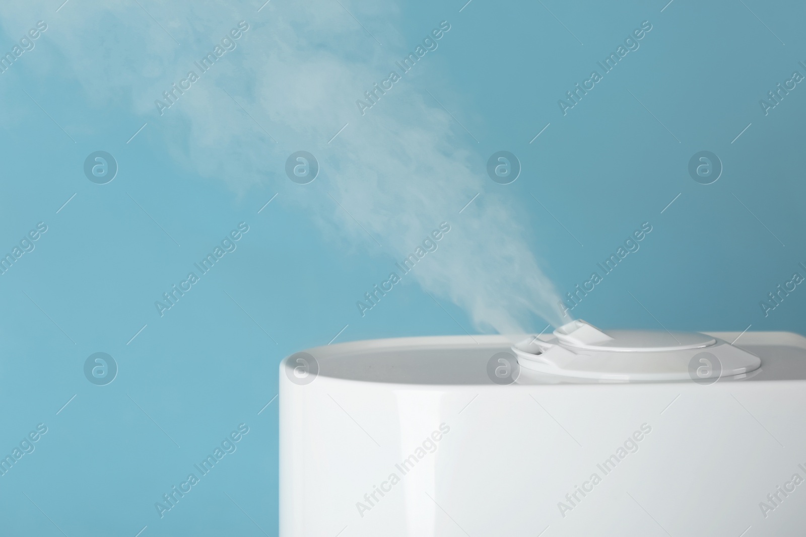 Photo of Modern air humidifier on light blue background, closeup. Space for text