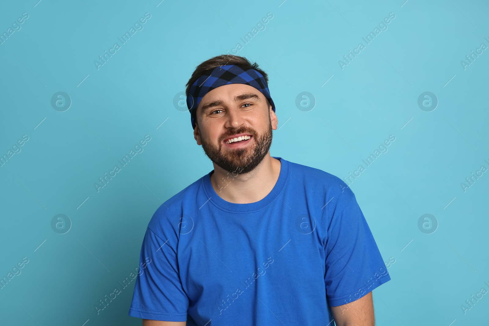 Photo of Fashionable young man wearing stylish bandana on light blue background
