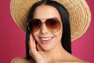 Beautiful woman wearing sunglasses on pink background, closeup