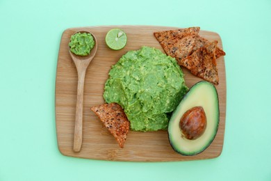 Delicious guacamole made of avocados, nachos and cut fruit on color background, top view