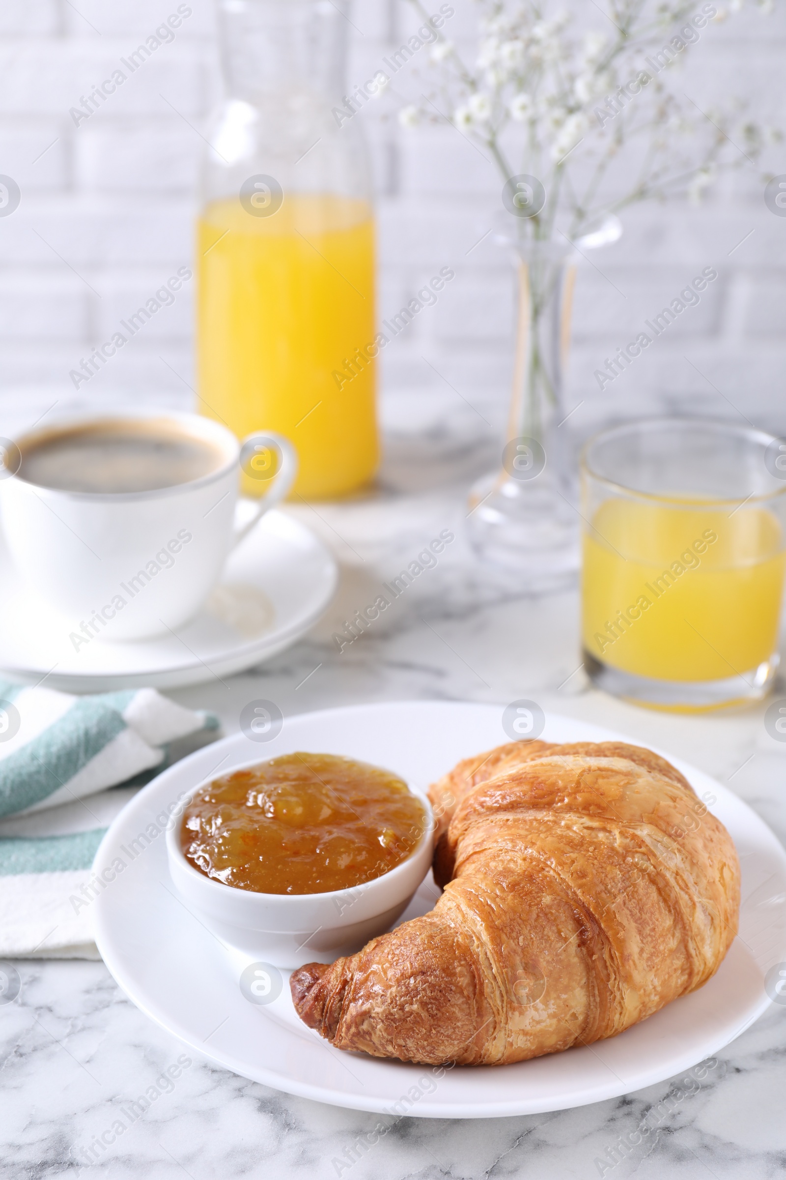 Photo of Tasty breakfast. Fresh croissant and jam on white marble table