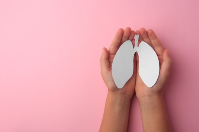 Photo of Child holding paper human lungs on pink background, top view. Space for text