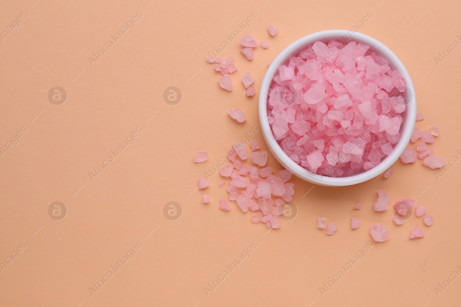 Photo of Plate with pink sea salt on beige background, top view. Space for text