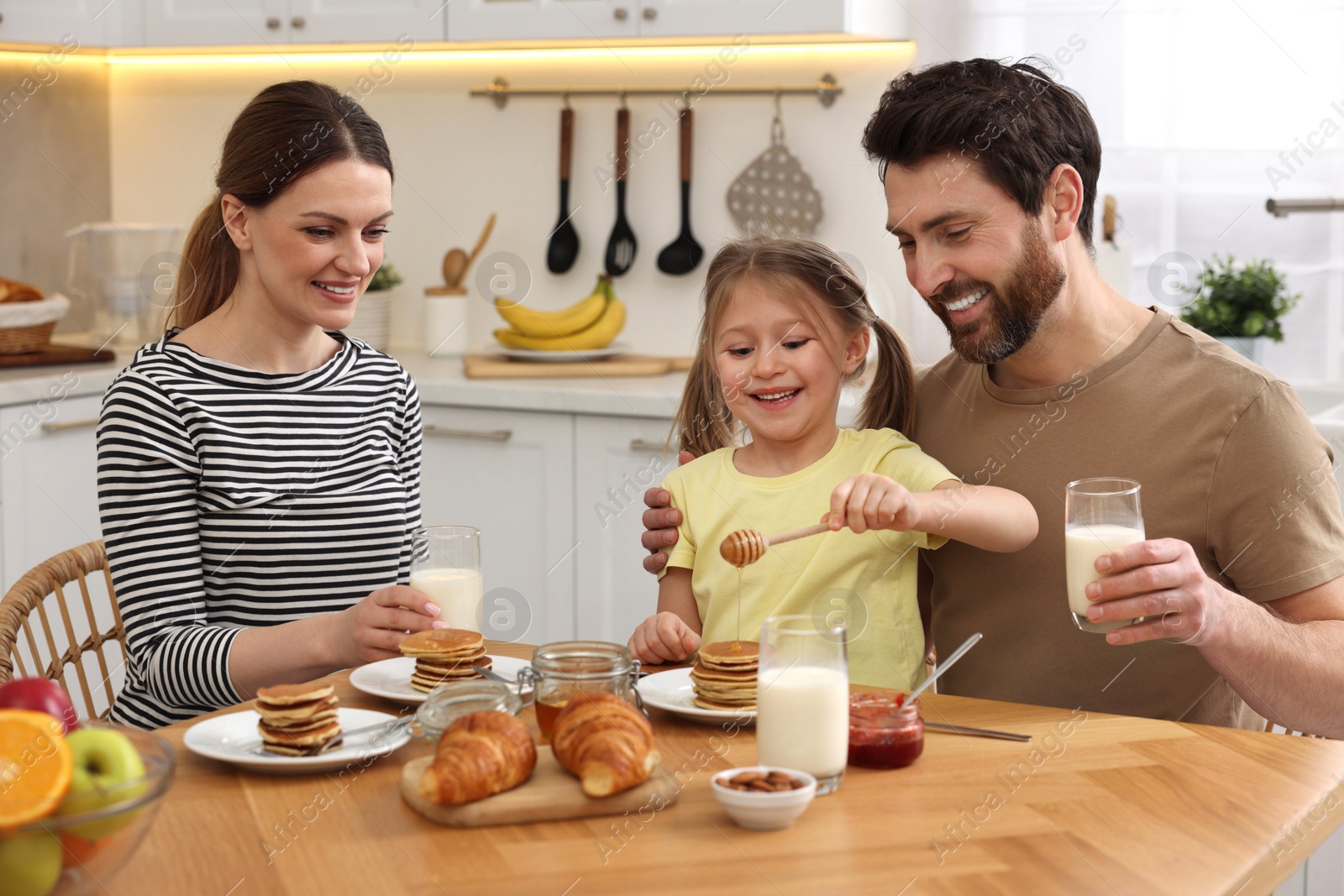 Photo of Happy family having breakfast at table in kitchen