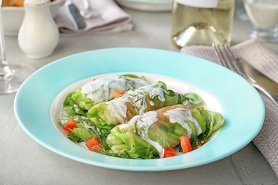 Photo of Plate with stuffed cabbage leaves and sour cream on table