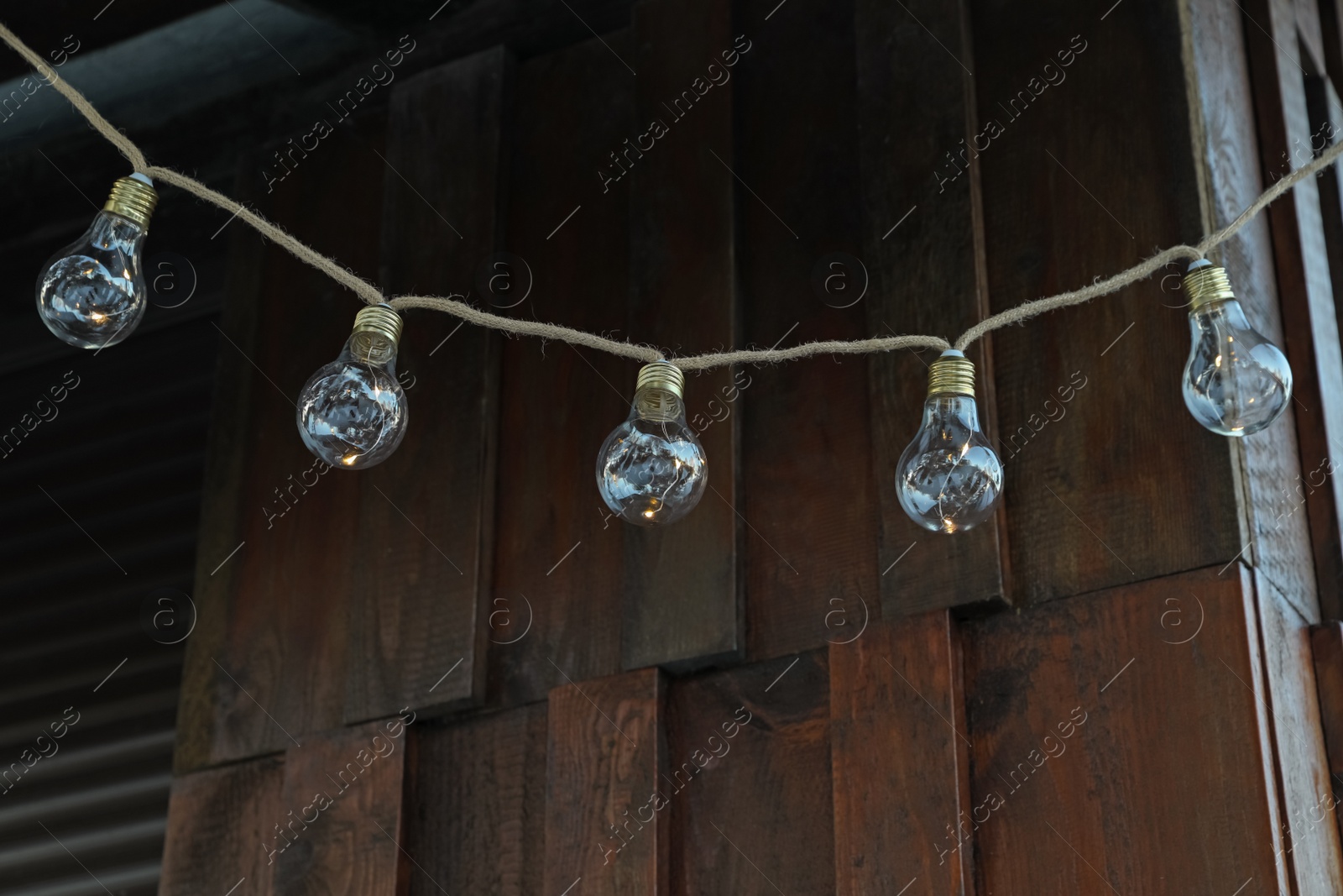 Photo of Beautiful garland of lamp bulbs hanging outdoors. String lights