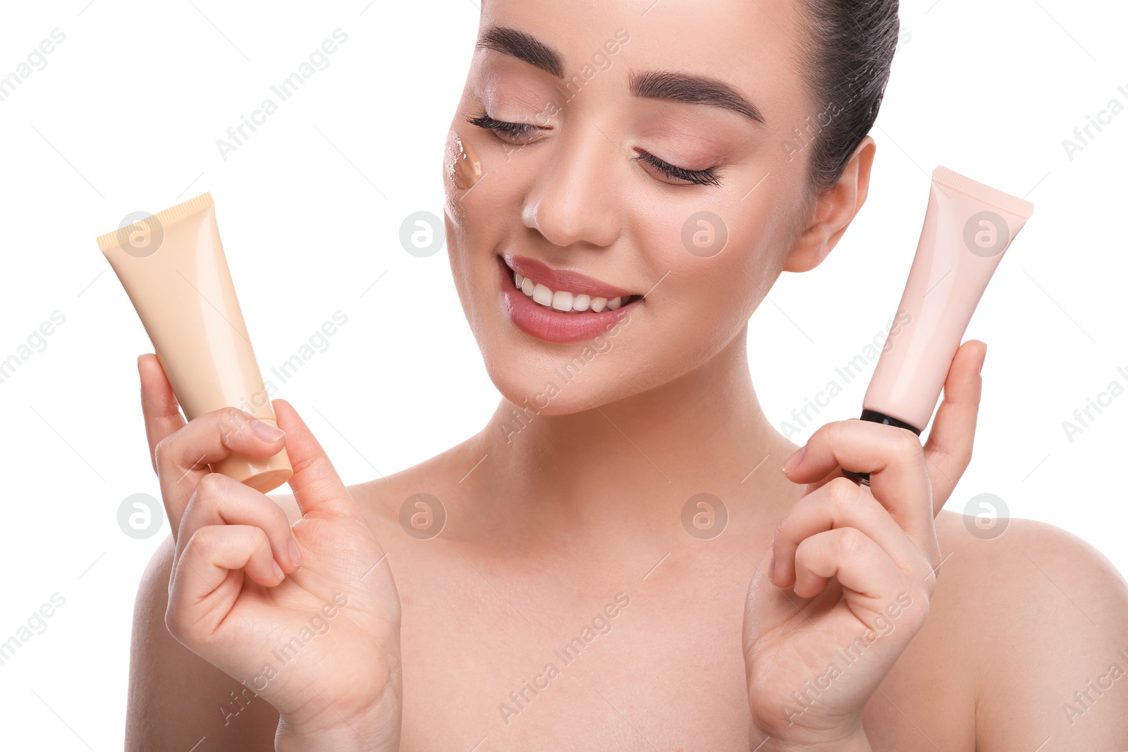 Photo of Woman holding tubes of foundation on white background