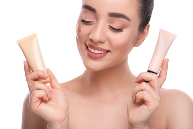 Photo of Woman holding tubes of foundation on white background