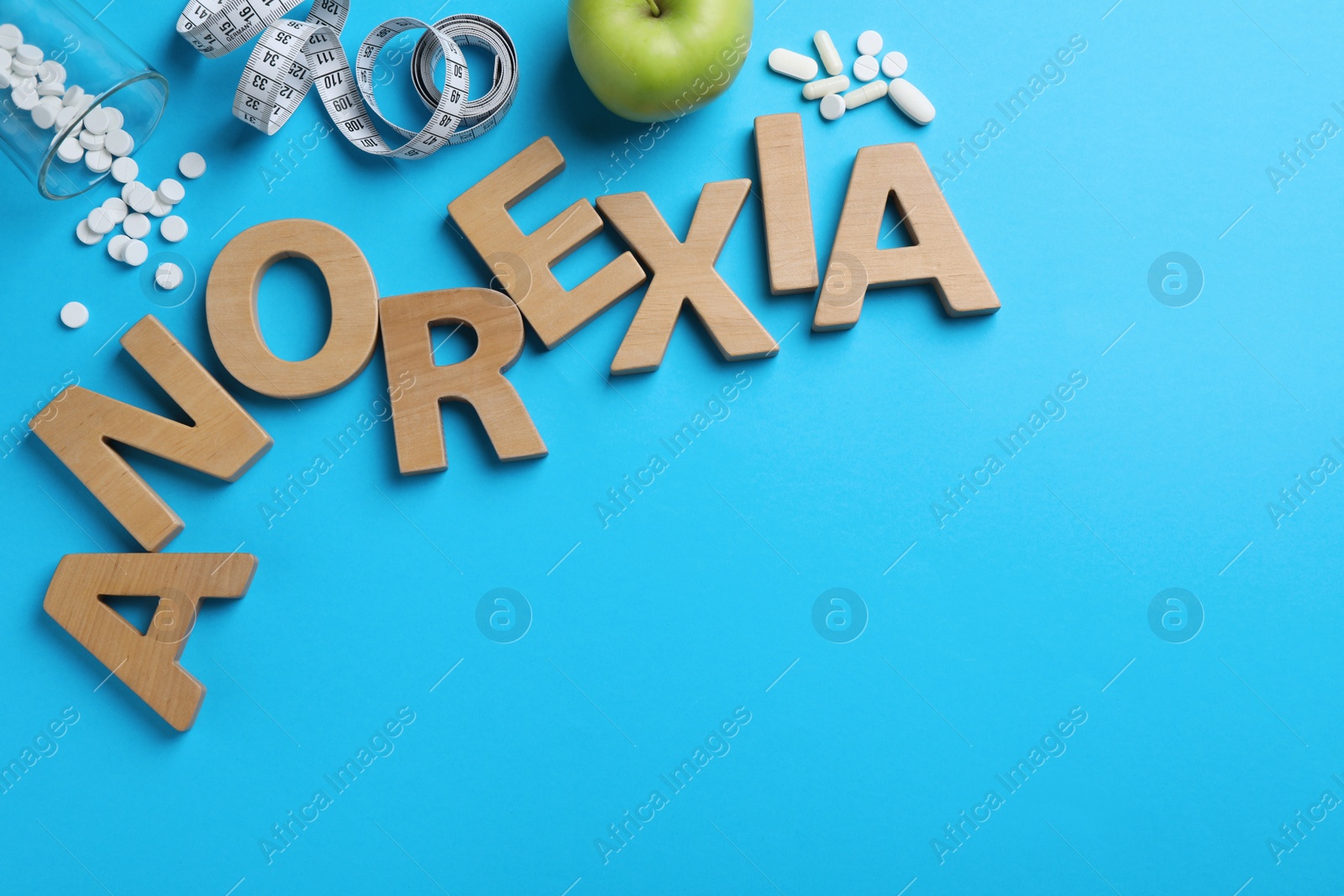 Photo of Flat lay composition with word Anorexia of wooden letters on light blue background. Space for text