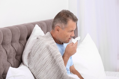 Photo of Man suffering from cough and cold in bed at home