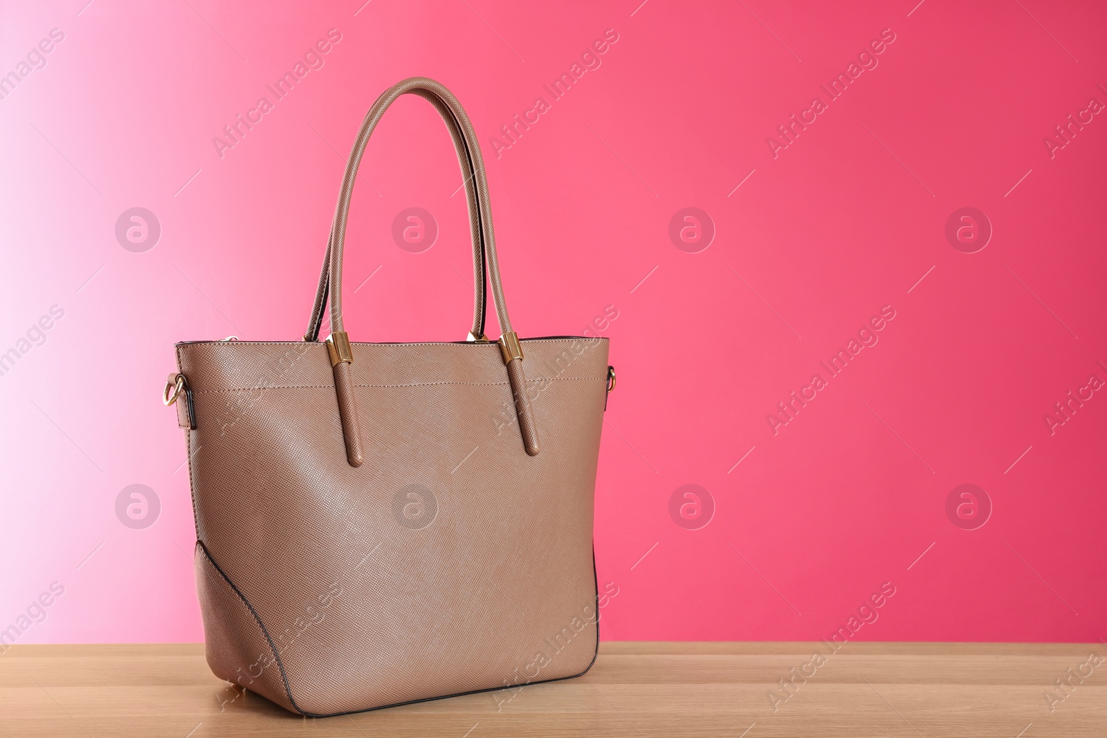 Photo of Stylish woman's bag on wooden table. Space for text