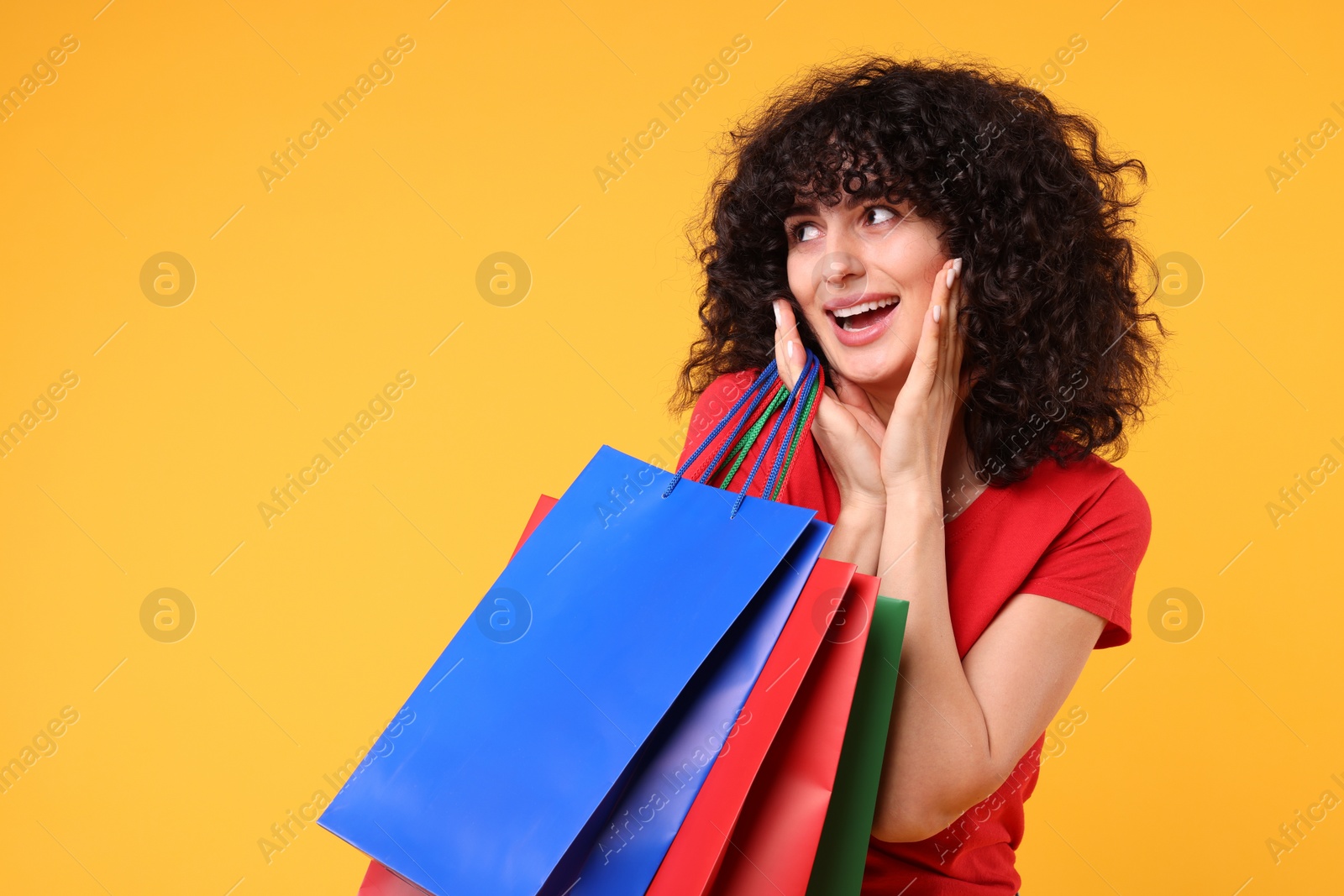 Photo of Happy young woman with shopping bags on yellow background