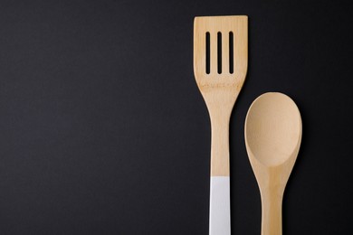 Photo of Wooden kitchen utensils on black background, flat lay. Space for text